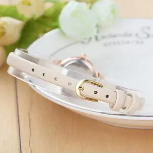 Elegant women's watch with cream leather strap and gold buckle on a wooden desk