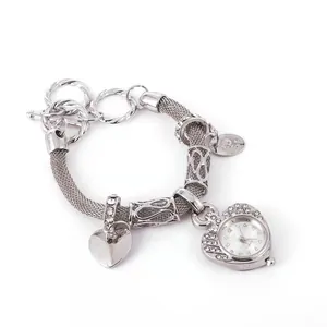 Dettaglio dell'orologio bracciale a maglia argento con ciondolo a cuore e charms lucidi