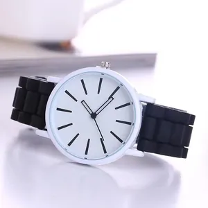 Close-up of a minimalist white dial watch with black silicone strap and matte casing