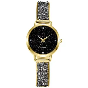 Detail of gold watch with black starry dial and quartz movement on white background