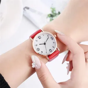 Gros plan d'une montre femme minimaliste avec bracelet en cuir rouge et boîtier or rose