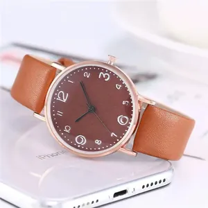 Gros plan d'une montre à quartz minimaliste or rose avec bracelet en cuir marron