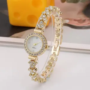 Dettaglio dell'orologio dorato da donna con lunetta in strass e cinturino geometrico