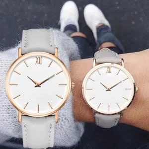Close-up of rose gold watch with white dial, Roman numerals, and grey leather strap