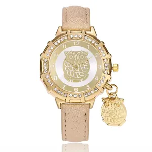 Detail of owl pendant and gold dial with sparkling champagne leather strap on watch