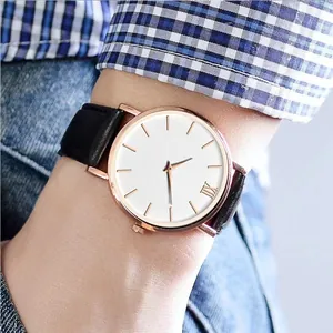 Close-up of a minimalist rose gold watch with white dial and black leather strap