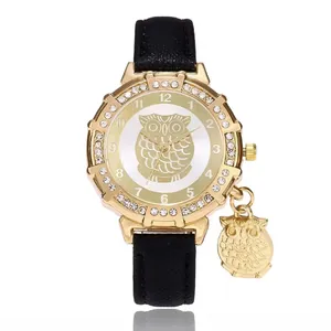 Detailed view of women's gold owl watch with rhinestone bezel and black leather strap
