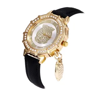 Detail view of a gold owl pendant watch with diamond bezel and black leather strap