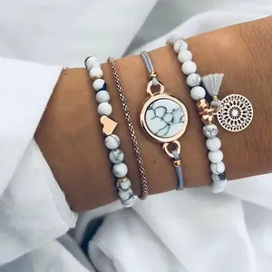 Détail d'un ensemble de quatre bracelets bohèmes avec perles blanches, pompons et pendentifs