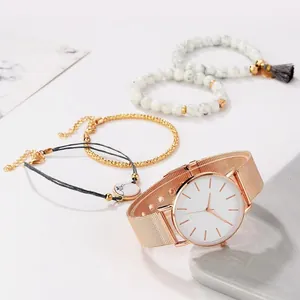 Gros plan d'une montre en maille or rose et de bracelets en perles de marbre blanc