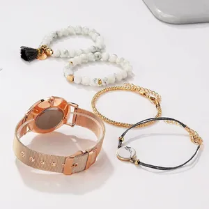 Détail d'une montre en maille or rose et d'un ensemble de bracelets en marbre blanc sur fond blanc