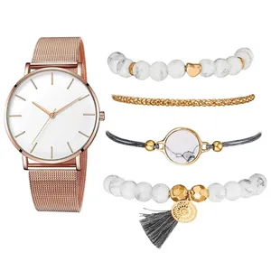 Détail de la montre à maille milanaise or rose et du set de bracelets en marbre