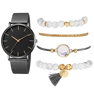 Détail d'un coffret montre en or rose et bracelets bohèmes avec perles et breloques