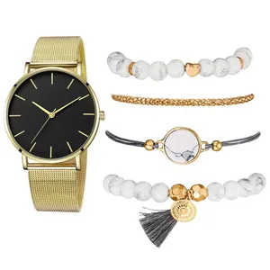 Détail d'une montre en maille dorée avec cadran noir et quatre bracelets en perles bohème
