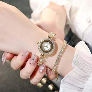 Nahaufnahme eines goldenen Damenuhr- und Strass-Armband-Sets mit Perlmutt-Zifferblatt am Handgelenk