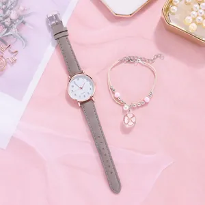 Close-up of a women's quartz watch with grey leather strap and floral charm bracelet