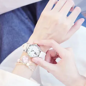 Nahaufnahme der weißen Lederuhr mit Katzen-Zifferblatt und Armband mit Blumen-Anhänger