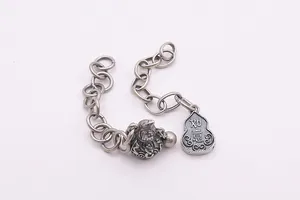 Macro detail of S925 sterling silver chain with vintage Fu and Ruyi gourd charms