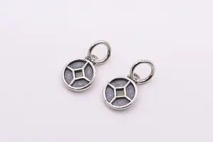 Détail macro de pendentifs en argent 925 en forme de pièce avec finition oxydée vintage