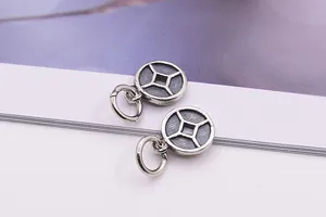 Vue macro de deux breloques pièces de monnaie en argent S925 avec trou carré pour bijoux DIY