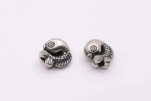 Macro shot of two vintage S925 sterling silver koi fish beads with detailed scales and textures