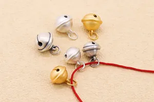 Nahaufnahme matter S999 Glocken-Anhänger in Gold und Silber an einer roten Kordel