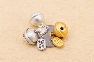 Dettaglio di campanelli in argento S999 in oro e argento con ciondoli portafortuna incisi