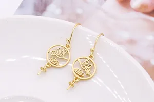 Macro view of matte gold crane and cloud hollow earrings for DIY pearl mounting
