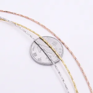 Three-tone S925 silver box chains in gold, rose gold and silver next to a coin