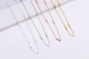 Detail view of silver, rose gold and gold cylinder bead cross necklaces on a platform