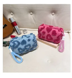 Detail of plush heart-patterned cosmetic bags in blue and pink on a quilted sofa