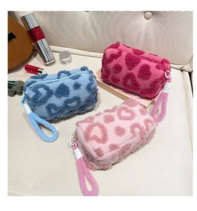 Detail of plush heart-patterned cosmetic bags in blue and pink on a cozy sofa setting