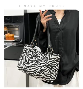 Close-up of zebra pattern tote bag with black handles and gold ring hardware details