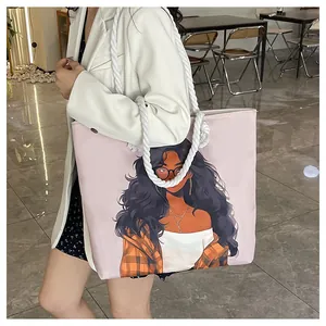 Detail of canvas tote bag featuring an artistic portrait and thick white rope handles