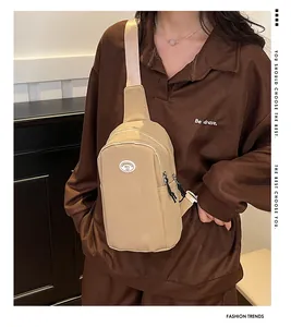 Close-up of khaki crossbody chest bag with adjustable strap and front zipper pocket detail