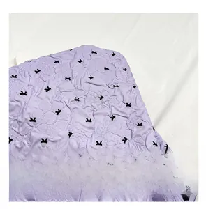 Detail of purple bubble texture fabric with black bow patterns and 3D crinkle effect