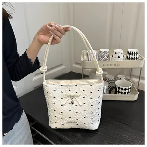 Detailed view of cream-white bucket bag featuring 3D bow texture and silver heart pendant