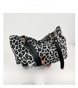 Detail of zebra print tote bag featuring black faux leather strap and golden hardware