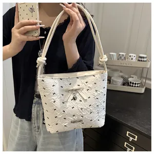 Detailed close-up of white bucket bag with black floral print and silver heart charm