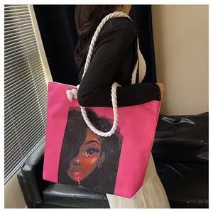 Detail of pink canvas tote bag featuring an artistic character print and white rope handle