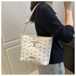 Detail of white textured shoulder bag featuring black bow patterns and heart pendant