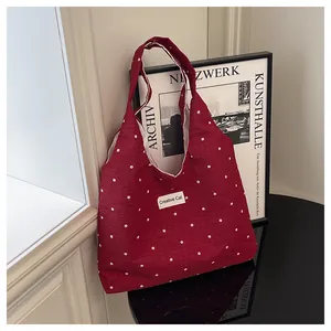 Detalle de bolso tote granate con flores y etiqueta Creative Cat en superficie pulida
