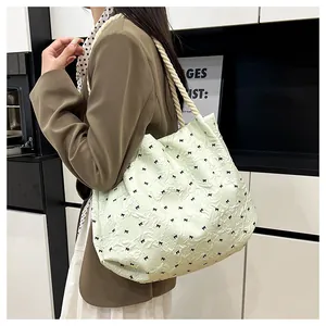 Detail of mint green pleated tote with bow patterns and thick rope handles worn by a model
