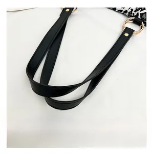 Close-up of black leather handles with gold hardware on a zebra pattern tote bag