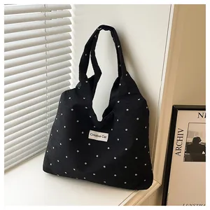Detalle de bolso tote de lona negra con patrón de flores y etiqueta de Creative Cat