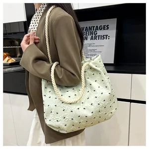 Shoulder shot of a light green seersucker tote bag with black bows and rope straps