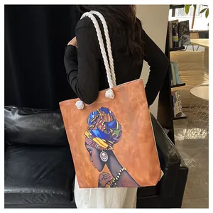Canvas tote bag with African woman print and thick cotton rope handles shown on shoulder