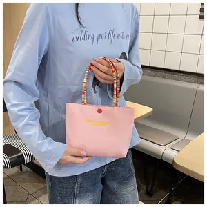 Detailed shot of pink fabric tote with colorful beaded handle and yellow embroidery