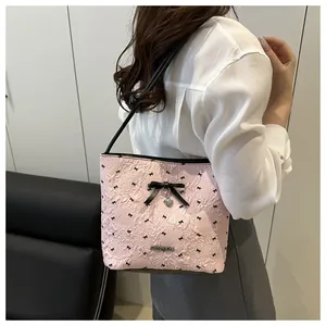 Detail of pink quilted shoulder bag with black bow embroidery and heart charm pendant