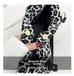 Detail of a zebra print tote bag with magnetic snap buttons and black leather trim